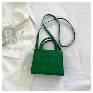 Détail du petit sac carré vert avec motifs de cœurs embossés et texture en cuir PU brillant