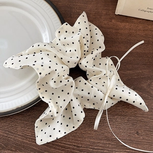 Close-up of cream polka dot scrunchie with bow and ribbon on wooden table