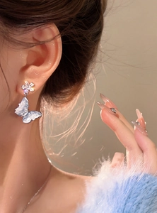 Detailed view of elegant icy blue butterfly drop earrings worn by a model for a chic look