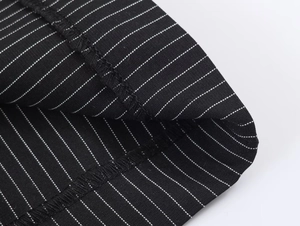 Detailed macro view of black sequin fabric with white striped patterns and fine stitching