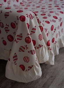 Detail of Christmas themed beige sofa cover with red festive prints and ruffled edge