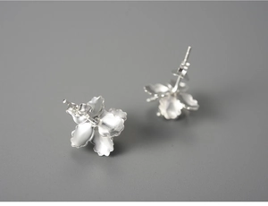 Macro detail of intricate 925 silver begonia flower earrings with matte metal petals