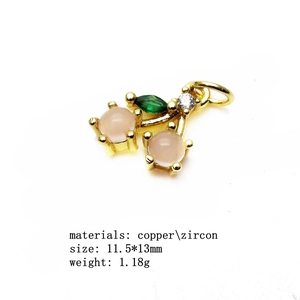 Detailed view of cherry charm with pink and green zircon stones on copper base