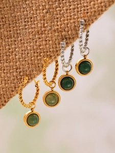 Detailed macro shot of vintage twisted gold and silver hoops with green agate pendants