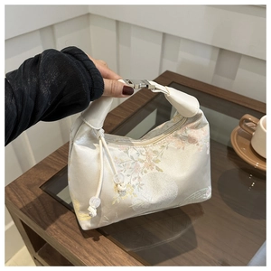Close-up of silk floral embroidery handbag with leather handle and metal buckle detail