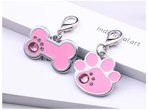 Detailed shot of pink paw and bone shaped pet tags with sparkling rhinestones and metal clips