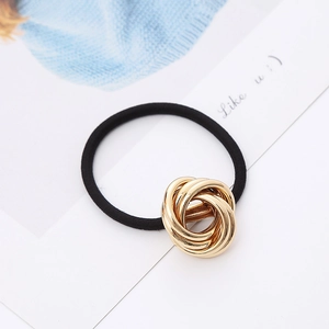 Detail of high-elastic black hair tie featuring a knotted gold metallic multi-ring charm