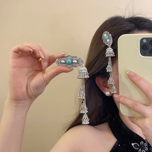 Detailed shot of ethnic silver hair clip with turquoise stone and bell tassels