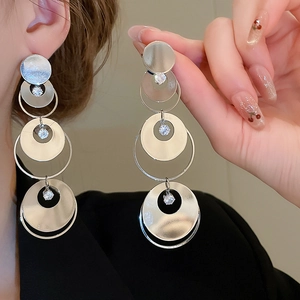 Detail of silver round tassel earrings with zircons on model with black suit