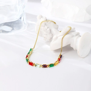 Detailed close-up of a gold necklace with colorful square-cut gemstones on a white statue