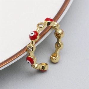 Close-up of golden adjustable ring with micro-set zircon and red evil eye enamel detail