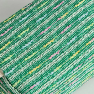 Macro shot of green tweed fabric with colorful neps and texture on the travel pouch