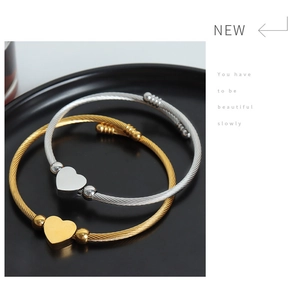 Detail of heart charm wire bracelets in gold and silver finish on black display