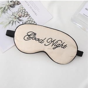 Detail of silk sleep mask with Good Night embroidery and adjustable strap in champagne