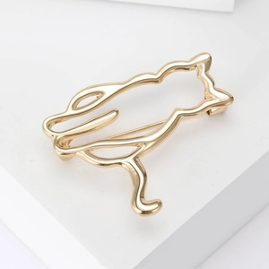 Close-up of a minimalist gold cat brooch with hollow design on a white platform