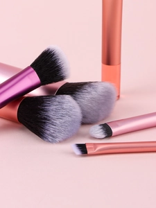 Close-up of 10 mini makeup brushes with rose gold handles and bicolor bristles in a set