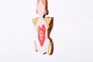 Detail of wooden angel ornament with red heart and gold painted wings for Christmas trees