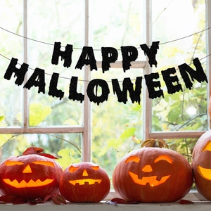 Black glitter Happy Halloween banner with scary drip font hung over glowing pumpkins