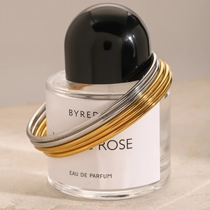 Polished stainless steel minimalist bracelets stacked on a perfume bottle display