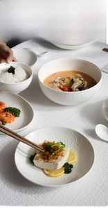 Detailed top view of white embossed ceramic tableware set with elegant floral relief textures