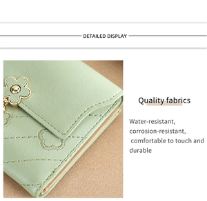 Detail of light green wallet featuring floral stitching and a metal flower buckle closure