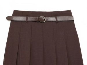 Détail de la taille d'une jupe plissée marron foncé avec ceinture et boucle argentée
