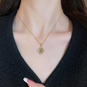Close-up of gold-plated flower necklace with gray gemstone and diamond accents on model