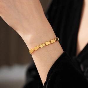 Detailed close-up of a gold gourd-shaped link bracelet with hammered texture and polished finish