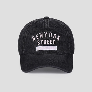 Detail of washed black denim baseball cap with pink and white embroidered New York text