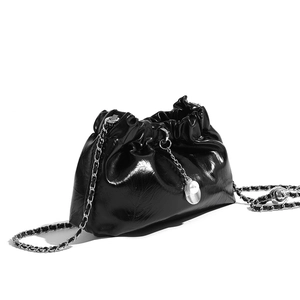 Detail of black pleated cloud bag featuring silver chain and decorative pearl charm