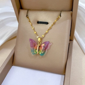 Macro detail of butterfly pendant with colorful gradient resin wings and gold foil accents