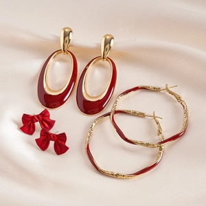 Retro 6-piece set of gold-tone red enamel bow and oval hoop earrings on silk background