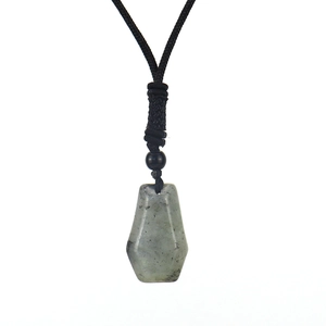 Detailed macro view of the hexagonal natural grey-green stone pendant on black woven cord