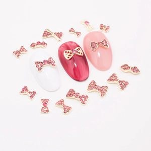 Macro view of gold bow nail charms with pink rhinestones on colorful nail tips
