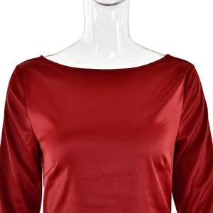 Detail of red satin long-sleeved dress showing smooth glossy fabric and neckline
