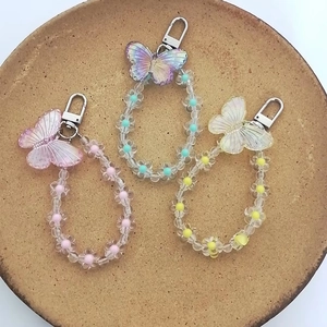 Close-up of colorful butterfly charms with transparent flower beads on a ceramic tray