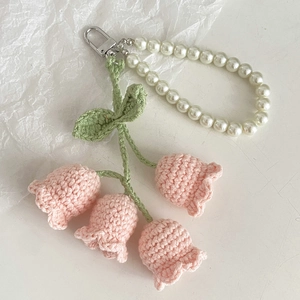 Detail view of pink crochet lily of the valley flowers with pearls and silver clasp