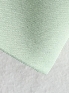 Close-up of mint green fabric texture and tailoring on a women's V-neck blazer