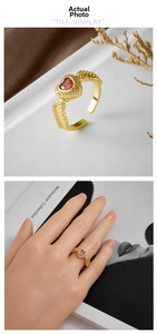 Detailed close-up of a gold-plated heart ring with red zircon and feather texture