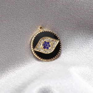 Makroaufnahme vom Evil-Eye-Anhänger mit blauen Strasssteinen auf Seidenstoff