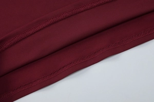 Détail du haut en dentelle bordeaux montrant la couture à double aiguille et la maille