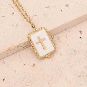Golden stainless steel necklace with rectangular cross pendant on a textured stone surface