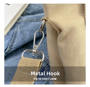 Detail of the polished silver metal hook and reinforced woven strap on the canvas tote bag