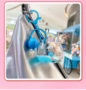 Détail du porte-clés ours bleu avec liquide et paillettes attaché à un sac à main