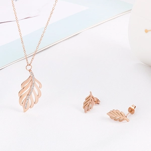 Gros plan sur l'ensemble collier et boucles d'oreilles feuilles en or rose avec cristaux