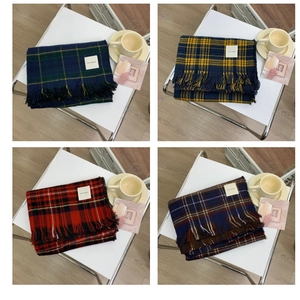 Detail view of the woven label and fringe edges on a classic plaid winter scarf