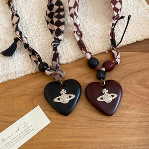 Detailed view of heart pendants with Saturn orb rhinestones and textured fabric cords