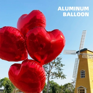 18 inch red heart-shaped aluminum foil balloon set against a blue sky with a windmill