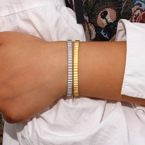 Macro shot of minimalist gold and silver stainless steel bangles with vertical textures