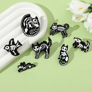 Detail shot of assorted black and white skeletal animal enamel pins on a decorative tray